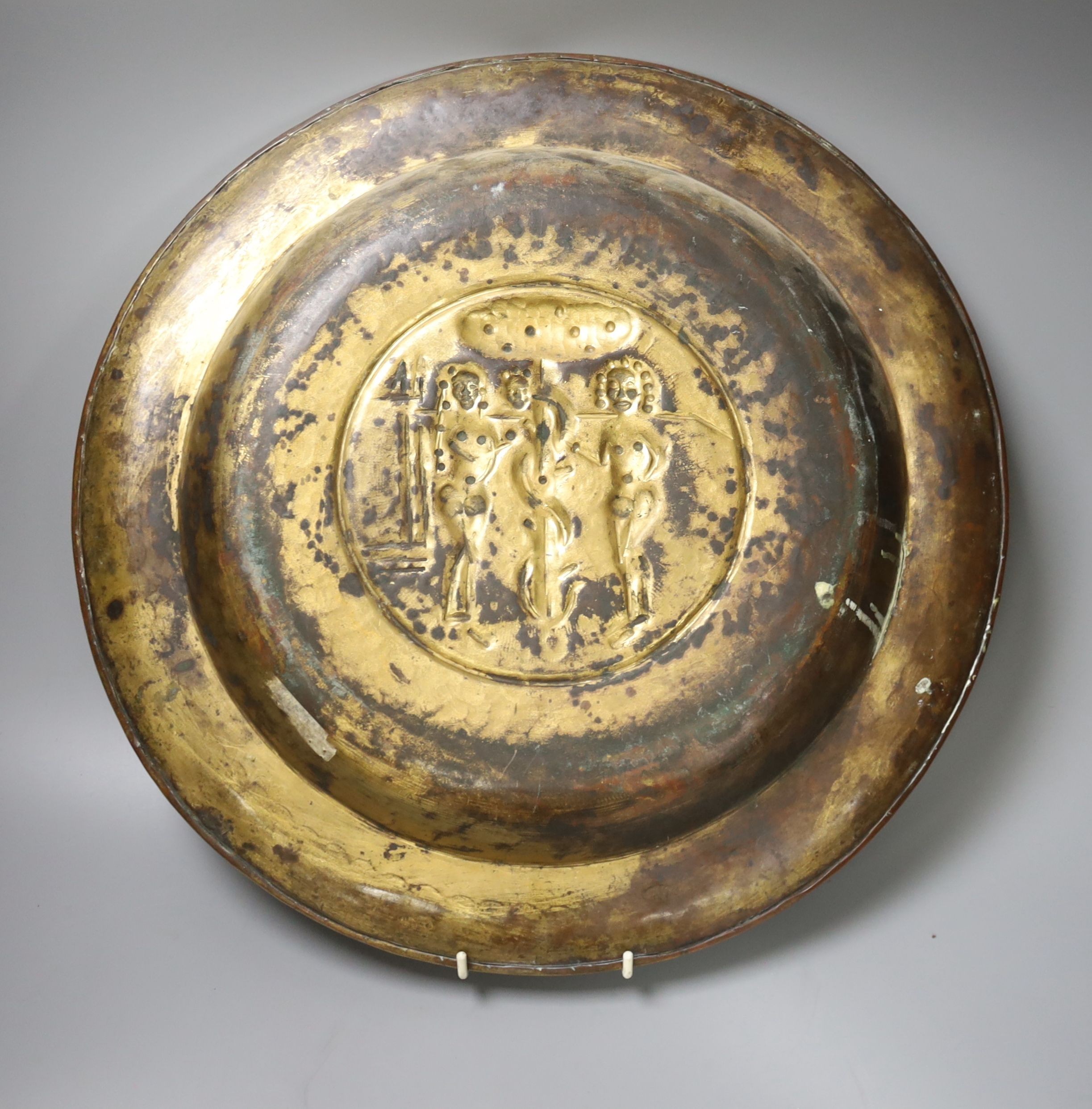 A large Nuremberg brass alms dish, 17th century, depicting Adam and Eve within a twisted foliate and floral border, with stylised armorial shields, 42cm